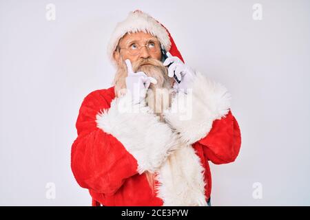 Alter älterer Mann trägt weihnachtsmann Kostüm Sprechen am Telefon ernstes Gesicht Denken über Frage mit der Hand auf dem Kinn, nachdenklich über verwirrende id Stockfoto