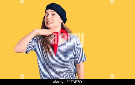 Junge schöne blonde Frau trägt französisch Baskenmütze und gestreiftes T-Shirt Hals mit Hand als Messer schneiden, drohen Aggression mit wütender Gewalt Stockfoto