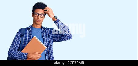 Junger afroamerikanischer Mann trägt Student Rucksack halten Buch besorgt und gestresst über ein Problem mit der Hand auf der Stirn, nervös und besorgt für c