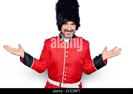 Mittelaltersstattliche wales Wachmann trägt traditionelle Uniform auf weißem Hintergrund lächelnd zeigt beide Hände geöffnet Handflächen, Präsentation und Werbung Stockfoto