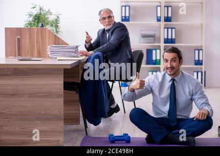 Zwei Mitarbeiter, die am Arbeitsplatz körperliche Übungen machen Stockfoto