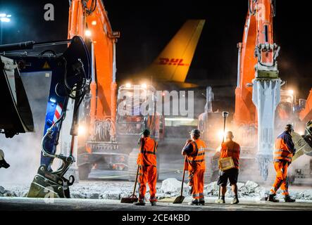 23. Juli 2020, Hessen, Frankfurt/Main: Mehrere Bauarbeiter beobachten Bagger mit pneumatischen Hämmern. Für rund 35 Millionen Euro saniert die Fraport AG einen der wichtigsten Rollenbahnen in 250 Baunächten am Flughafen. Dies muss nach und nach erfolgen, da nur die Nachtstunden für die Arbeiten zur Verfügung stehen und der sanierte Bereich bereits am nächsten Tag wieder einsatzbereit sein muss. Foto: Andreas Arnold/dpa Stockfoto