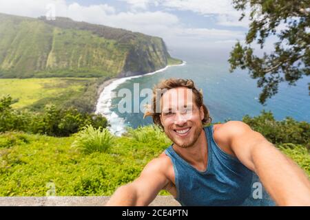 Selfie-Tourist-Wanderer, der ein Selbstporträt am Waipio Valley Lookout in Big Island, Hawaii, macht. Männlicher Rucksacktourist, der lächelt, wenn das Kameratelefon eingeschaltet ist Stockfoto