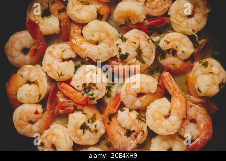 Babygarnelen mit Petersilie und Knoblauch werden in einer Pfanne gekocht, Draufsicht, flach liegend, Nahaufnahme Stockfoto