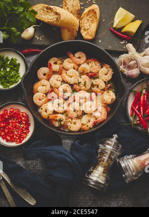 Gebratene Baby Shrimps auf Eisenpfanne und frischen Kräutern und Zutaten serviert. Draufsicht, flach liegend Stockfoto