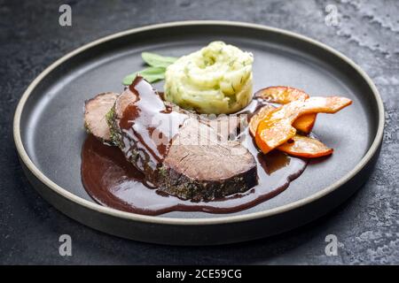 Traditionelle geröstete Rinderherz mit gebratenen Kürbisscheiben und püriert Kartoffeln in Soße Rotwein-Sauce als Nahaufnahme auf einem Modernes Design Stockfoto