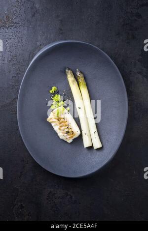 Gebratenes dänisches Kabeljaufischfilet mit weißem Spargel und wasabi Algenkaviar als Draufsicht auf einem modernen Design Platte mit Kopie sp Stockfoto