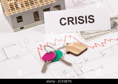 Schlüssel mit Home-Form, Währungen Dollar, Abwärtsgraphen und Inschrift Krise auf elektrischen Baudiagramme des Hauses. Immobilienkrise Stockfoto
