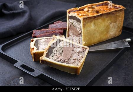 Traditionelle französische Pate en Croute mit Gänsefleisch und Leber Angeboten mit Quitte als Nahaufnahme auf einem modernen Design Gusseisen t Stockfoto