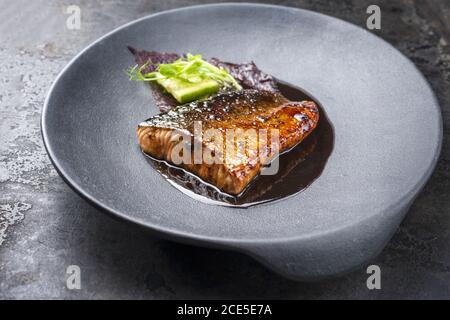 Japanisches Lachsfischfilet in minimalistischem Design mit Gemüse und Nori Glasiert in Teriyaki-Sauce als Nahaufnahme auf einem modernen Design pl Stockfoto