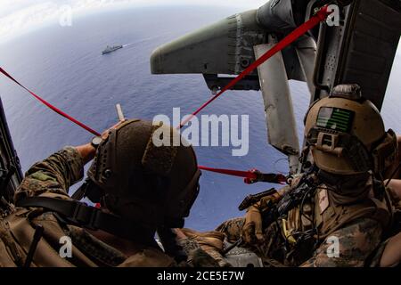 PHILIPPINISCHES MEER (Aug 26, 2020) Cpl. Colt Mullins mit der Maritime RAID Force (MRF), 31st Marine Expeditionary Unit (MEU), bietet Luftsicherheit während eines Besuchs, Bord, Suche, Und Beschlagnahme (VBSS) Mission auf einem MH-60S Sea Hawk Hubschrauber zugeordnet zu den Erzengeln des Hubschraubers Sea Combat Squadron (HSC) 25 Ablösung 6, nach dem Start von amphibischen Angriffsschiff USS America (LHA 6). VBSS ist Teil von Maritime Interception Operations, die darauf abzielen, feindliche Streitkräfte oder Lieferungen im maritimen Bereich zu verzögern, zu stören oder zu zerstören. Amerika, Flaggschiff der Amphibious Ready Group (ARG), 31. MEU-Team, IS Stockfoto