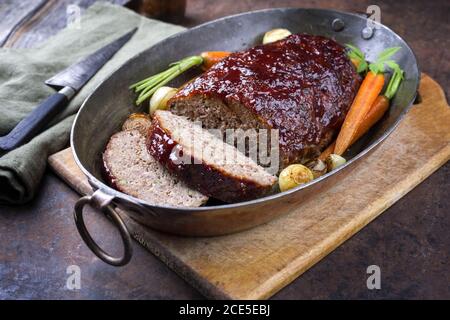 Traditionelles amerikanisches Hackbraten mit Ketchup aus Hackfleisch mit Karotten Und Zwiebel als Nahaufnahme in einem Kupfertopan Stockfoto