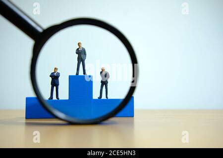 Business-Konzeptfoto – Miniatur des Geschäftsmannes steht auf Holz Podium Stockfoto
