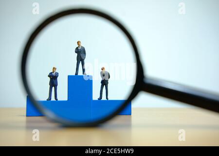 Business-Konzeptfoto – Miniatur des Geschäftsmannes steht auf Holz Podium Stockfoto