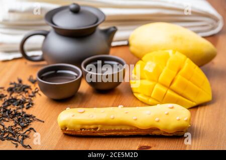Eclair ein französisches Cremeteig mit Mango-Geschmack zeigt die Vollfrucht-Puff und Nachmittagstee-Set Stockfoto