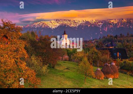 Atemberaubende ländliche Herbstlandschaft und alpines Dorf mit schönen Gärten. Bunte Laubbäume und spektakuläre Wolken über den verschneiten Bergen, Mag Stockfoto