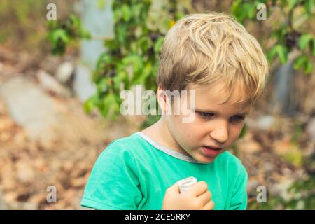 Hübsch niedlich blonde junge grün T-Shirt in schlechter Stimmung Blick nach unten. Künstlerische Emotionen und Gestik. Problem oder glückliche Kindheit, Verhaltenserziehung Stockfoto
