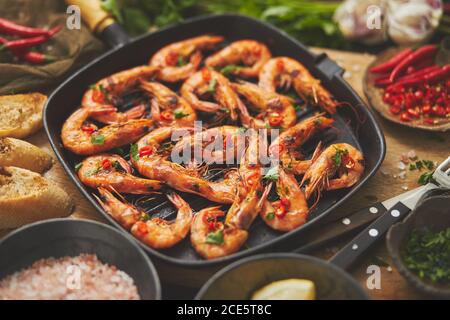 Leckere, appetitlich geröstete Garnelen Garnelen mit Gewürzen auf der Pfanne mit Zutaten auf rostigen Hintergrund Stockfoto