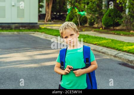 Lustig schelmisch niedlich blonde Junge mit Sommersprossen blauen Rucksack aus der Schule oder Kindergarten, künstlerische Emotionen Gesichtsausdruck. Micro Moments einfach Stockfoto