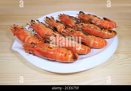 Platte mit Flaming Grilled River Garnelen auf Holztisch serviert Stockfoto