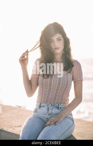 Seriöse Frau, die am Meer auf die Kamera schaut Stockfoto