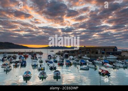 Lyme Regis, Dorset, Großbritannien. August 2020. Wetter in Großbritannien. Die Wolken über dem Cobb Harbour leuchten orange bei Sonnenaufgang bei Lyme Regis in Dorset am Feiertagsmontag. Bild: Graham Hunt/Alamy Live News Stockfoto