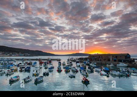 Lyme Regis, Dorset, Großbritannien. August 2020. Wetter in Großbritannien. Die Wolken über dem Cobb Harbour leuchten orange bei Sonnenaufgang bei Lyme Regis in Dorset am Feiertagsmontag. Bild: Graham Hunt/Alamy Live News Stockfoto