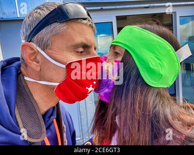 Glückliches Paar küsst sich gegenseitig mit Gesundheit Gesichtsmasken während Covid-19. Stockfoto