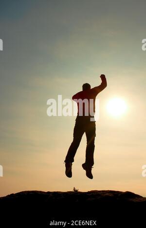 Springender Mann. Junge verrückte Mann springt auf bunten Himmel Hintergrund.Silhouette der springenden Mann und schönen Sonnenuntergang Himmel. Stockfoto