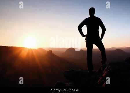 Ein Mann hat seine Hände auf Hüften. Sportler Silhouette in der Natur bei Tagesanbruch. Stockfoto