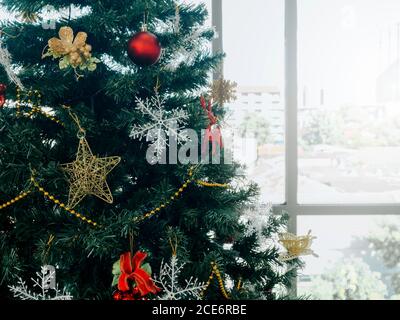 Weihnachtsbaum Dekoration im Büro in der Nähe Fenster Glas auf Stadt und Winter Himmel Hintergrund mit Kopieplatz. Nahaufnahme Weihnachtsbaum Hintergrund. Stockfoto