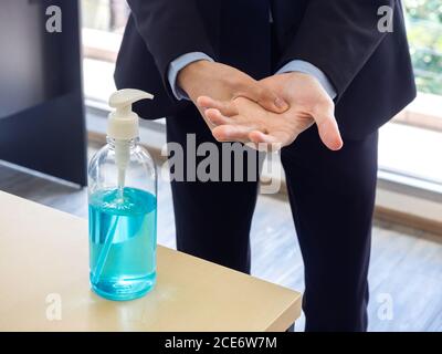 Händedesinfektion mit Alkoholgel. Hände eines Geschäftsmannes, der das Desinfektionsmittel auf dem Tisch im Büro verwendet, Coronavirus-Prävention. Ein Geschäftsmann, der Gelhand verwendet Stockfoto