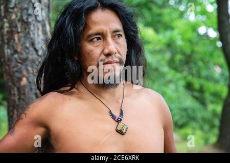 Junger amerikanischer Ureinwohner im Wald mit Kristallquarz Halskette Stockfoto