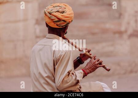 Indien - 29. Oktober 2012: Rückansicht eines nicht erkennbaren Mannes, der in der Wüste steht und traditionelle indische Flöte spielt Stockfoto