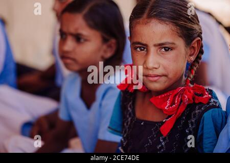 Indien - 30. Oktober 2012: Gesellschaft von fröhlichen indischen Schülerinnen sitzen auf Steinboden in der Nähe der Schule im Dorf während des Tages Stockfoto