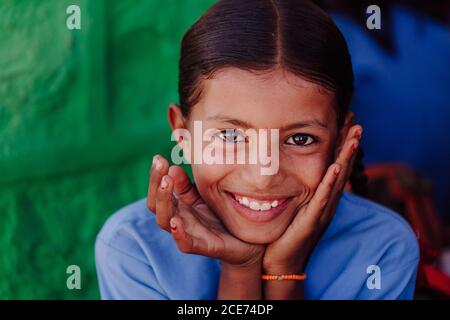 Indien - 30. Oktober 2012: Charmantes indisches Mädchen mit braunen Augen, die das Gesicht berühren und fröhlich auf die Kamera schauen Stockfoto