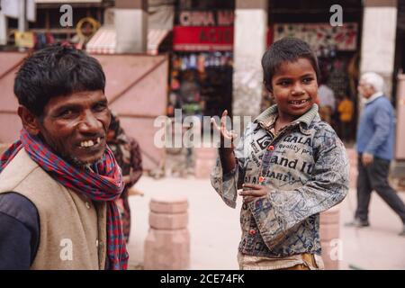 Indien - 9. November 2012: Lächelnder indischer Vater und Kind in schmutziger Kleidung stehen auf der alten Straße in der Stadt Stockfoto