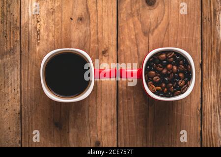 Draufsicht Komposition aus roten Tassen mit geröstetem aromatischem Kaffee Bohnen und frische heiße Energizing americano zusammen auf Holz gelegt Tabelle Stockfoto