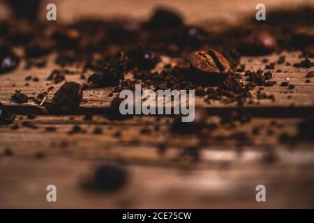 Aromatische geröstete Kaffeebohnen auf dunklem Holztisch in der Nähe platziert Frischen gemahlenen Kaffee verteilen Stockfoto