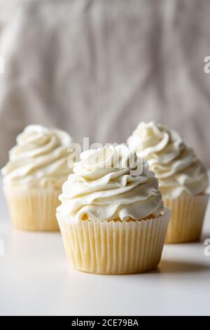 Leckere Vanille Cupcakes mit süßer Sahne auf Tablett gelegt Tabelle auf weißem Hintergrund Stockfoto