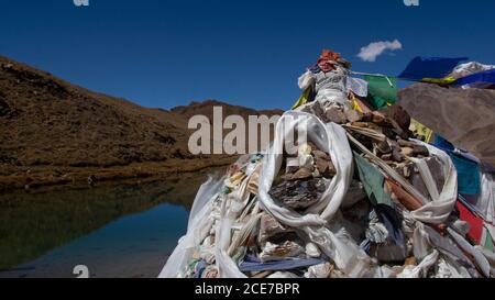 Ein Buddha Idol wird auf einem Schrein mit bedeckt gesetzt Buddhistische Gebetsfahnen am Ufer des Chandratal - A Höhensee in Himachal Pradesh mit klarem Stockfoto