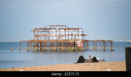 Brighton UK 31. August 2020 - früher Strandgänger in der Nähe von Brighton West Pier an einem schönen sonnigen Morgen, um den August Bank Holiday Montag beginnen . Die Prognose ist für sie viel kühler als normal in einigen Teilen von Großbritannien heute : Credit Simon Dack / Alamy Live News Stockfoto