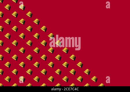 Ansicht der gelben Kaffeepads in geraden Reihen Als nahtloses Muster auf rotem Hintergrund Stockfoto