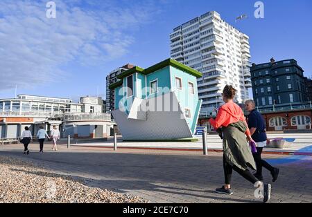 Brighton UK 31. August 2020 - Spaziergänger kommen an einem schönen sonnigen Morgen am Upside Down House an der Küste von Brighton vorbei, um den August-Feiertag Montag zu beginnen. Die Prognose ist für sie viel kühler als normal in einigen Teilen von Großbritannien heute : Credit Simon Dack / Alamy Live News Stockfoto