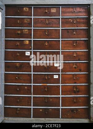 Archiv, das identische dunkelbraune Holzschubladen mit Zahlen darstellt Unebene Oberfläche mit Flecken in der Werkstatt Stockfoto