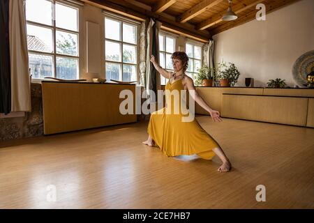 Seitenansicht einer fokussierten Frau, die barfuß im Studio steht Anjaneyasana und Yoga beim Aufschauen Stockfoto
