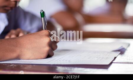 Hand der Schüler schriftlich und Prüfung mit Stress in Schulungsraum Stockfoto