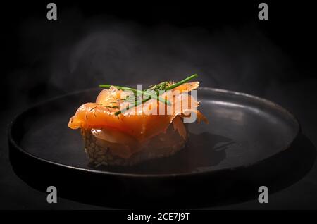 Geräucherter Lachs und Fenchelkräuter auf dem gesäuerten Brot Auf einem dunklen Teller und einem dunklen Tisch Stockfoto