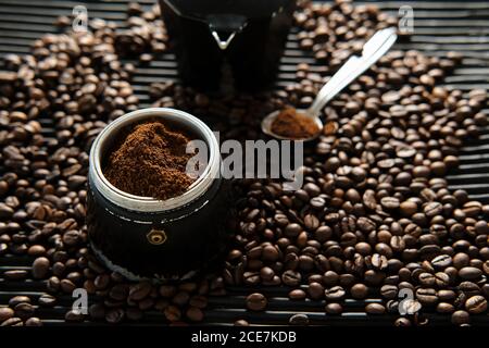 Von oben gemahlener Kaffee in traditioneller Kaffeemaschine platziert Auf dem Tisch mit verstreuten gerösteten Körnern Stockfoto