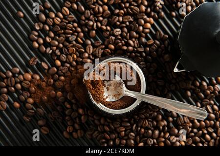 Von oben gemahlener Kaffee in traditioneller Kaffeemaschine platziert Auf dem Tisch mit verstreuten gerösteten Körnern Stockfoto